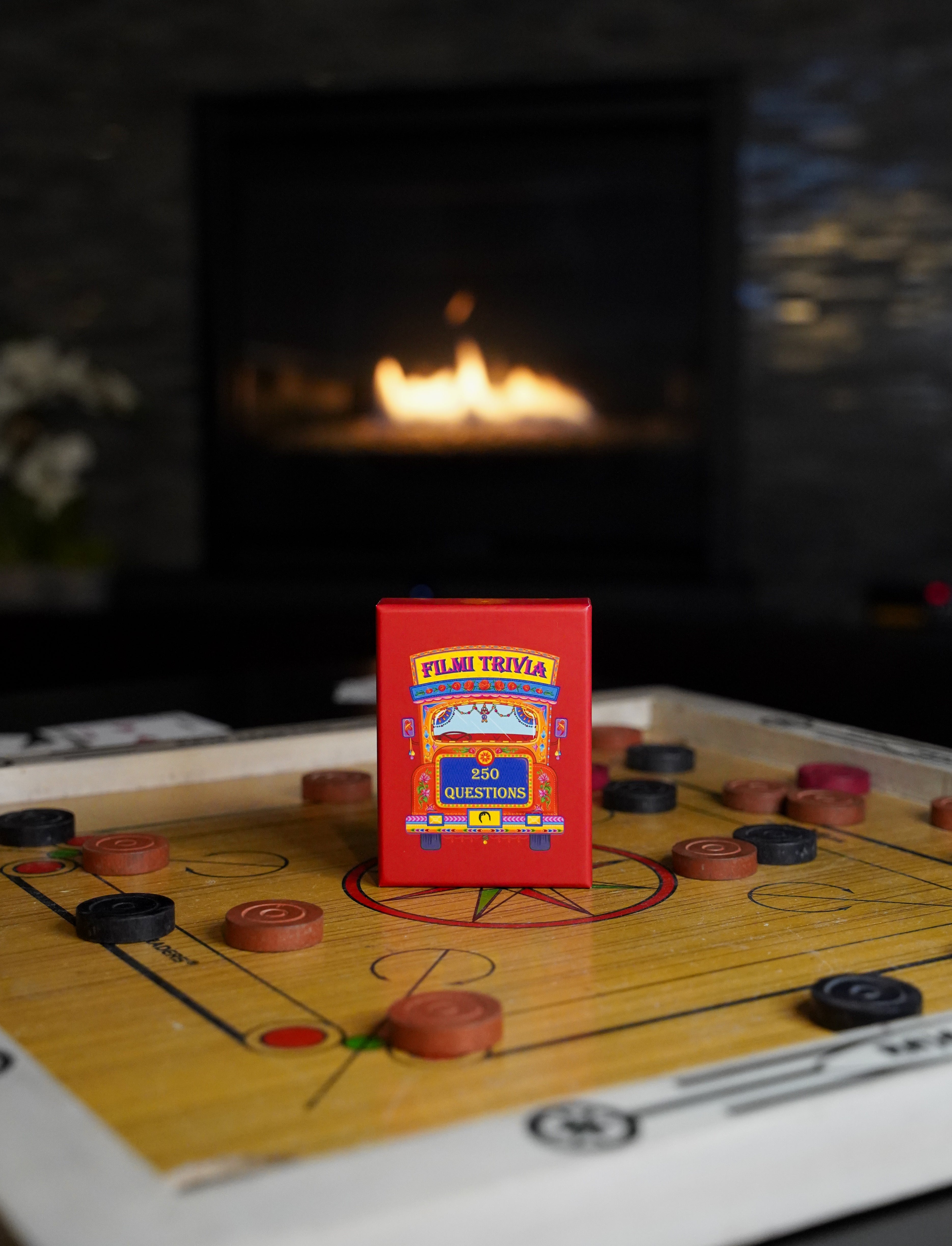 Film trivia, a Bollywood trivia card game, on a carrom board game with a fireplace in the background.