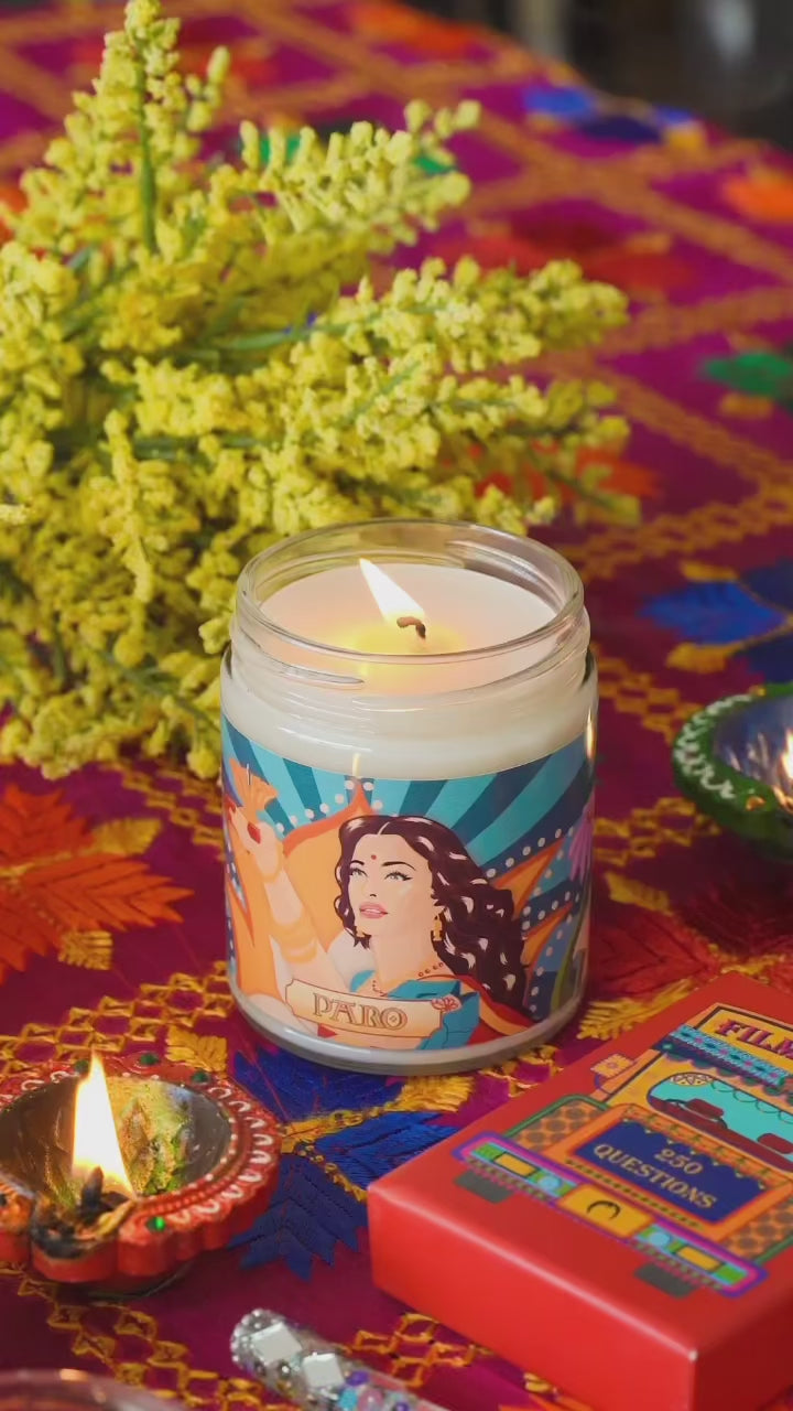 A video of a Diwali candle with artwork of Aishwarya Rai from the Bollywood movie Devdas lit on a table with diyas next to a copy of Filmi Trivia.
