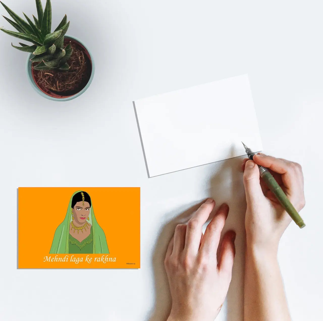 Person writing on a postcard featuring artwork of Kajol's mehndi look from the film Dilwale Dulhania Le Jayenge (1995)